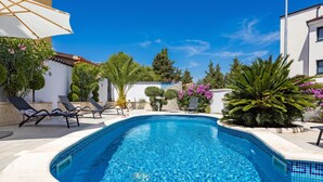 A swimming pool with lounge chairs, surrounded by greenery and a clear blue sky. - Villa Bianco Nero With Pool (Pula)
