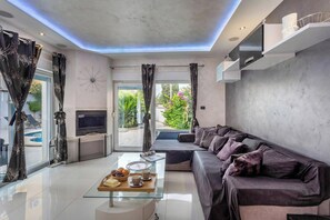 A modern living room with a glass coffee table, a sofa, and a TV. - Villa Bianco Nero (Pula)