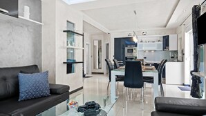 A modern living room with a glass coffee table, a black leather sofa, and a dining area with a glass table and chairs. - Villa Bianco Nero With Pool (Pula)