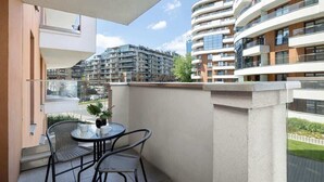 A balcony with a table and chairs, overlooking a modern apartment building.