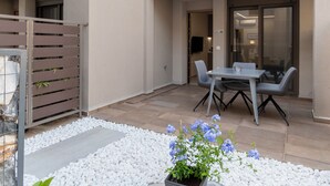 A modern outdoor patio with a dining table and chairs, surrounded by white pebbles and a potted plant. - SithoniaRS Seashell Maisonette (Νικήτη)