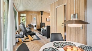 Ein gemütliches Zimmer mit Holzvertäfelung, einem Kamin und einer Essecke mit Tisch und Stühlen.
