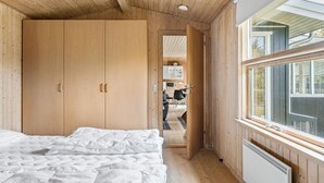 Ein Schlafzimmer mit Bett, Holzschrank und Fenster mit Blick.