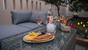Ein Tisch mit einer Weinflasche, zwei Gläsern, einem Teller mit Obst und Crackern sowie einem kleinen Korb.