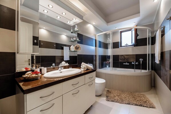 Une salle de bain moderne dotée d’un grand lavabo, d’une baignoire et d’une douche à parois de verre.