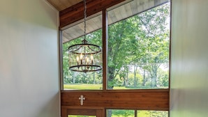 A wooden staircase leading to a deck with a glass door, a chandelier, and a view of greenery outside. - Chasing Birdies (Banner Elk)