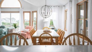 A dining area with a white table and wooden chairs, large windows, and a view of houses outside. - Private pool/spa, rooftop deck, 5min walk to beach (Corolla)