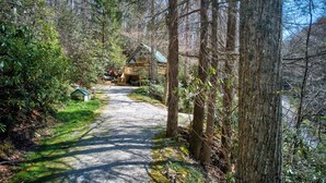 Une cabane située dans une zone boisée, accessible par un chemin de gravier.