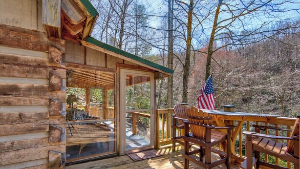 Une cabane en bois dotée d’une terrasse, de chaises en bois et d’un drapeau américain.