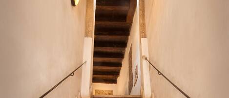 A staircase with a handrail on both sides, leading to a landing with a wooden ceiling.