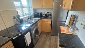 Una cocina compacta con armarios de madera, lavadora, estufa y refrigerador.