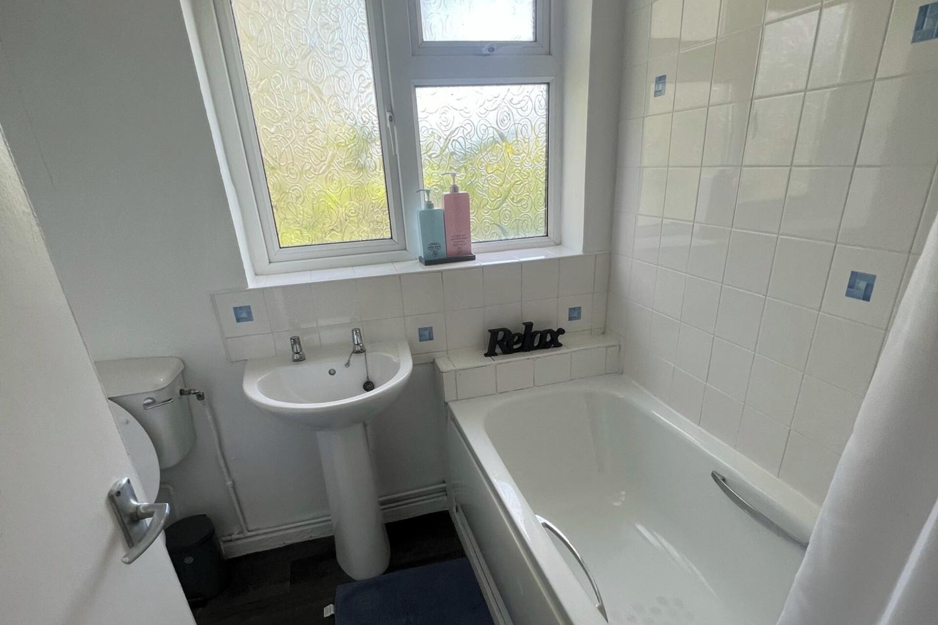 A bathroom with a white sink, a window, and a bathtub.