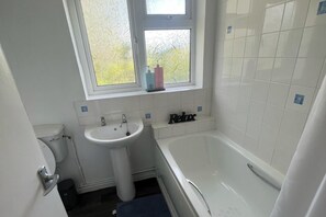 A bathroom with a white sink, a window, and a bathtub. - Serene Escape Cosy Apartment in Wolverhampton (Wolverhampton)