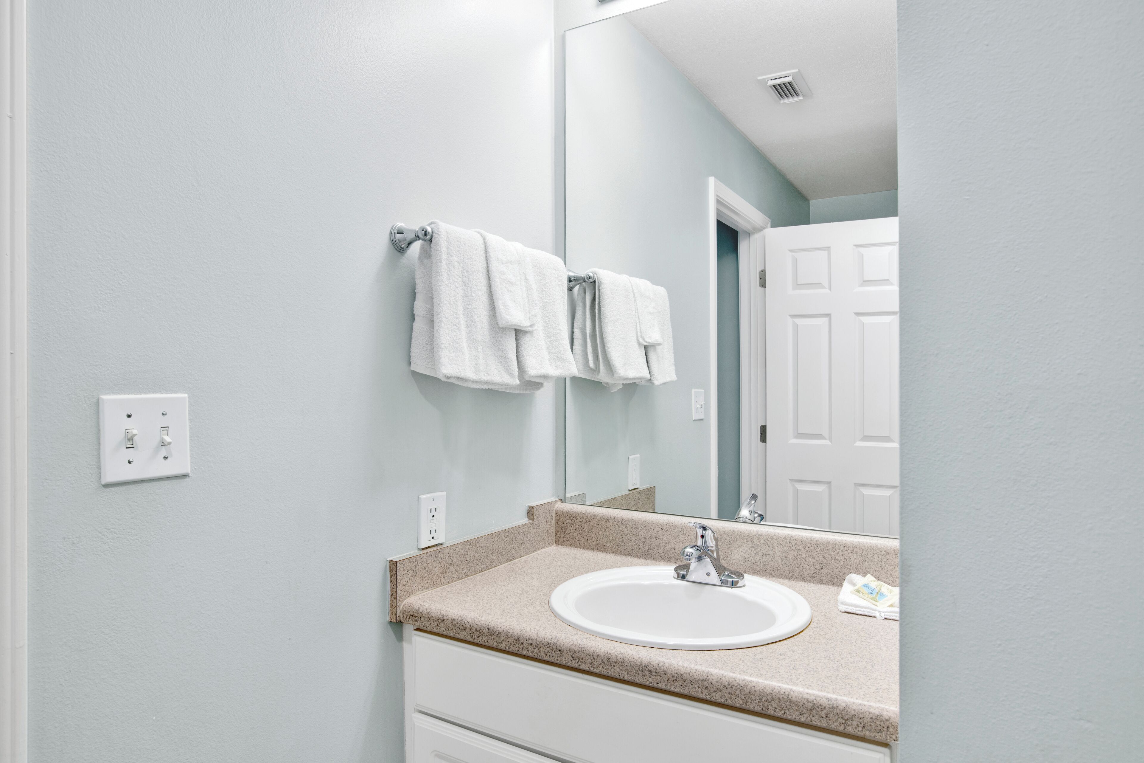A bathroom with a white sink, a mirror, and a towel rack.