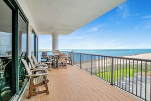 A balcony with a view of the ocean, furnished with chairs and a table.