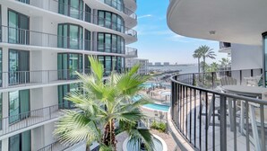 Un hôtel moderne doté de nombreux balcons, d’un espace piscine et offrant une vue sur la mer.