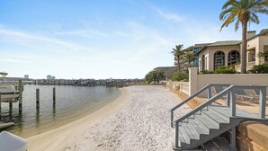 Une plage avec un escalier en bois menant à un bâtiment doté d’un balcon.