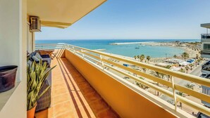 Un balcón con vista al mar, una playa y un cielo despejado.
