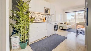 Un apartamento moderno con cocina, lavadora, comedor y balcón.