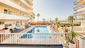 Zona de piscina con sillones de descanso y vista al mar.