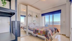 Habitación compacta con cama, escritorio y ventana con vistas.