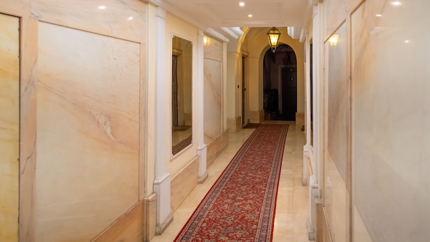 A hallway with marble walls, a red carpet, and a light fixture. - Navona Romantic House (Roma)