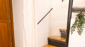 A staircase with wooden steps and black railings, a glass table with a chair, and a potted plant. - Navona Romantic House (Roma)