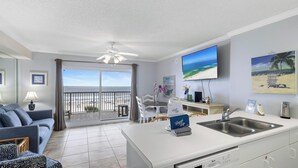 Ein modernes Wohnzimmer mit Balkon, einer Küche mit Spüle und einem Flachbildfernseher.