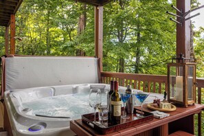 A hot tub with a wooden deck, surrounded by trees. - The Boulders (Boone)