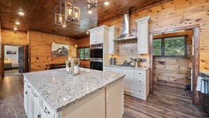A spacious kitchen with granite countertops, white cabinetry, and a large island. - Cranberry View Lodge (Newland)