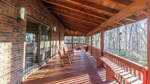 A covered porch with wooden beams, a brick wall, and a view of a forest. - Eagles Rest (Fleetwood)