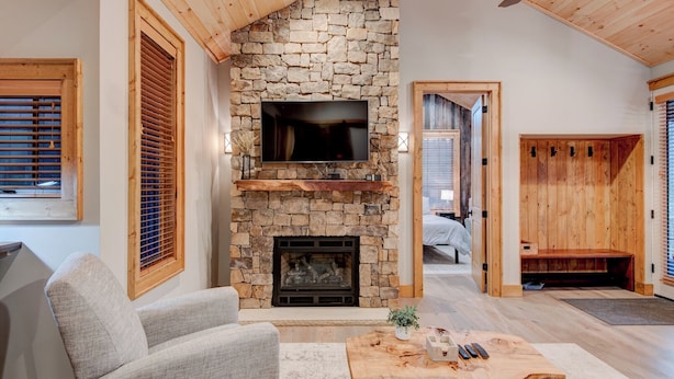 A cozy living room with a stone fireplace, a flat-screen TV, and a comfortable seating area. - Banner Bear (Banner Elk)