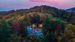 Ein modernes Haus, umgeben von einem Wald, mit einem Feldweg, der dorthin führt.