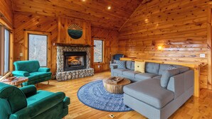 Ein Blockhaus-Interieur mit Kamin, zwei Sofas und einem runden Teppich.