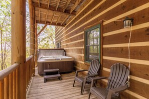 A wooden cabin with a hot tub, two Adirondack chairs, and a window with a view of trees. - A Moon River View (Boone)