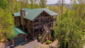 A wooden cabin with a green roof, a covered porch, and a staircase leading to a deck. - A Moon River View (Boone)