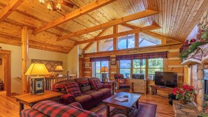 A cozy cabin interior with a wooden ceiling, a fireplace, a sofa set, and a television. - A Moon River View (Boone)