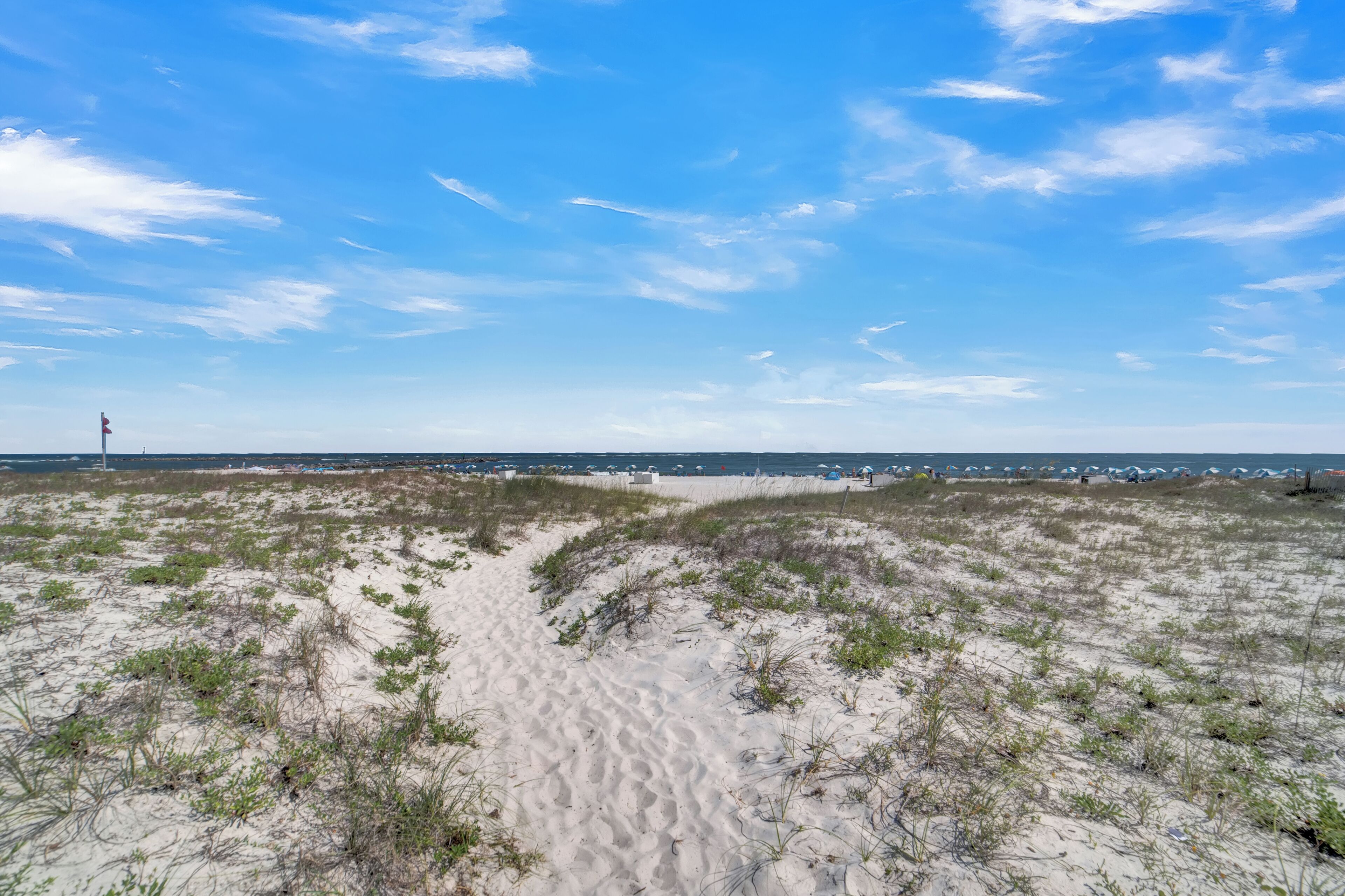 Une plage de sable avec des dunes et un ciel dégagé.