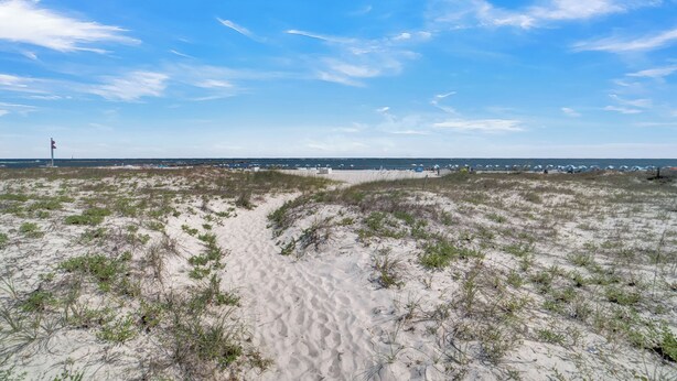 Een zandstrand met duinen en een heldere lucht.