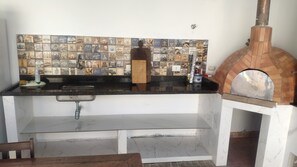 Compact kitchen area with pizza oven and modern countertop.
