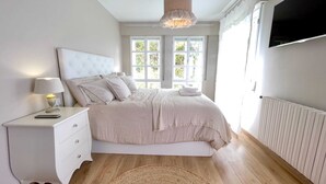 A bedroom with a bed, bedside table, lamp, and a view of the outdoors through large windows. - The Cliffs - Sabaido Mare (Manón)