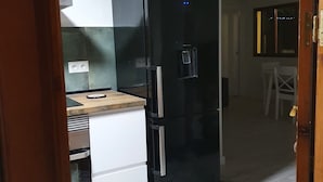 Una cocina compacta con un refrigerador negro, una encimera pequeña y un armario blanco.