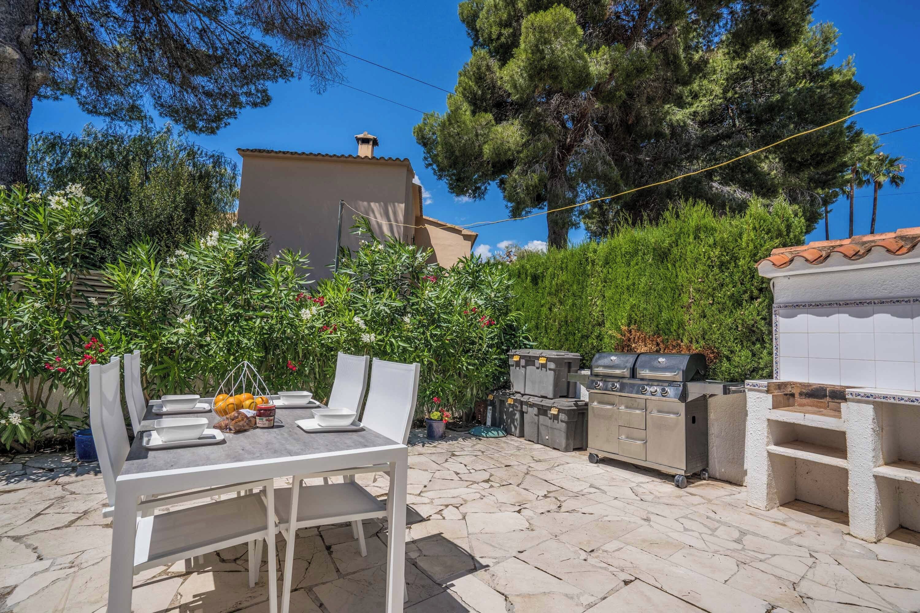 An outdoor patio with a dining table and chairs, a barbecue grill, and a tiled barbecue area.