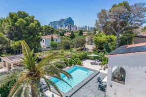 Zona residencial con piscina, palmeras y vista a un paisaje urbano con edificios altos y una montaña destacada al fondo.