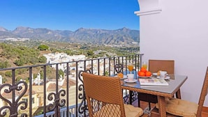 A balcony with a table set for breakfast, overlooking a mountainous landscape. - Villa Lara Pinta (Nerja)