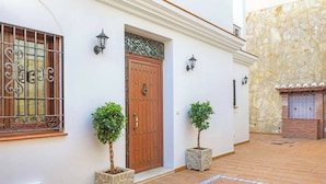 A building with a wooden door, two potted plants, and a stone wall. - Villa Lara Pinta (Nerja)