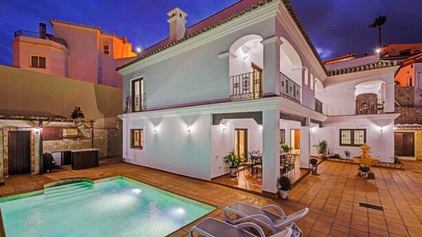 A two-story building with a swimming pool, outdoor seating, and a well-lit patio area. - Villa Lara Pinta (Nerja)