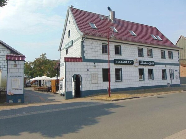 A two-story building with a tiled facade and a red roof. It has a sign indicating it is a restaurant named Balkan Grill.