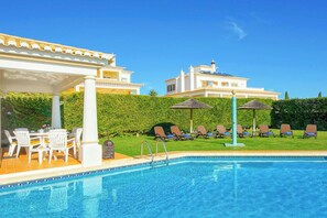 A pool area with lounge chairs and a covered seating area. - Villa Beatrice (Albufeira)