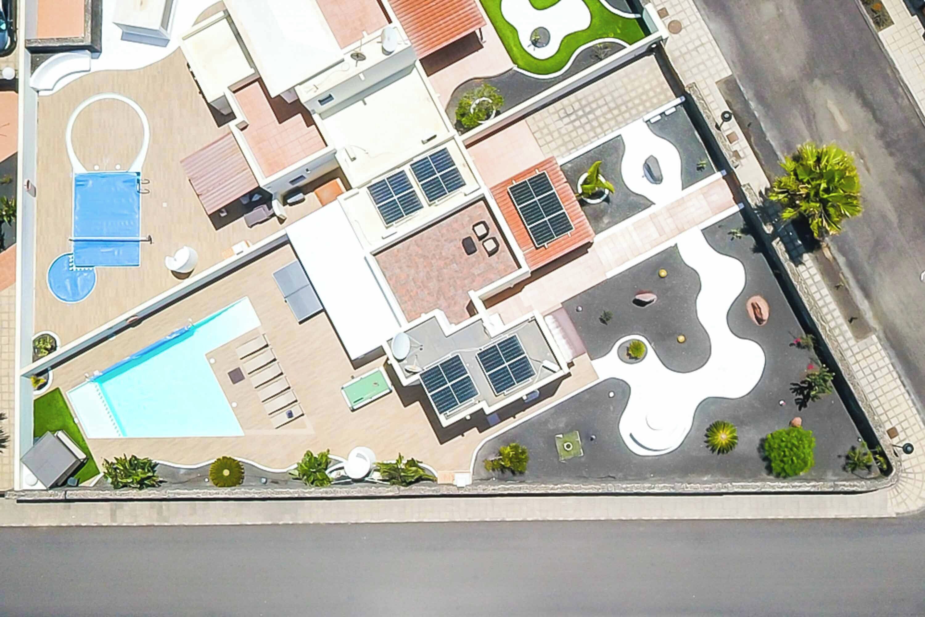 Oversigtsbillede af et hotel med swimmingpool, liggestole, tennisbane og anlagt have.